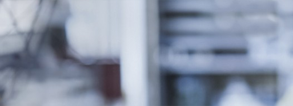 A blurred, out-of-focus background featuring shades of grey and white with indistinct shapes and lines.