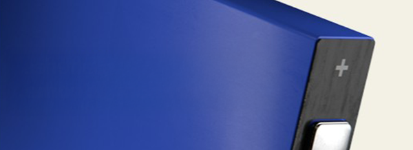 Close-up of a blue rectangular object with a black edge featuring a plus sign and a silver button.
